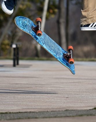 Skateboard flying through the air, the feet are visible. Image by <a href="https://pixabay.com/users/santa3-3503898/