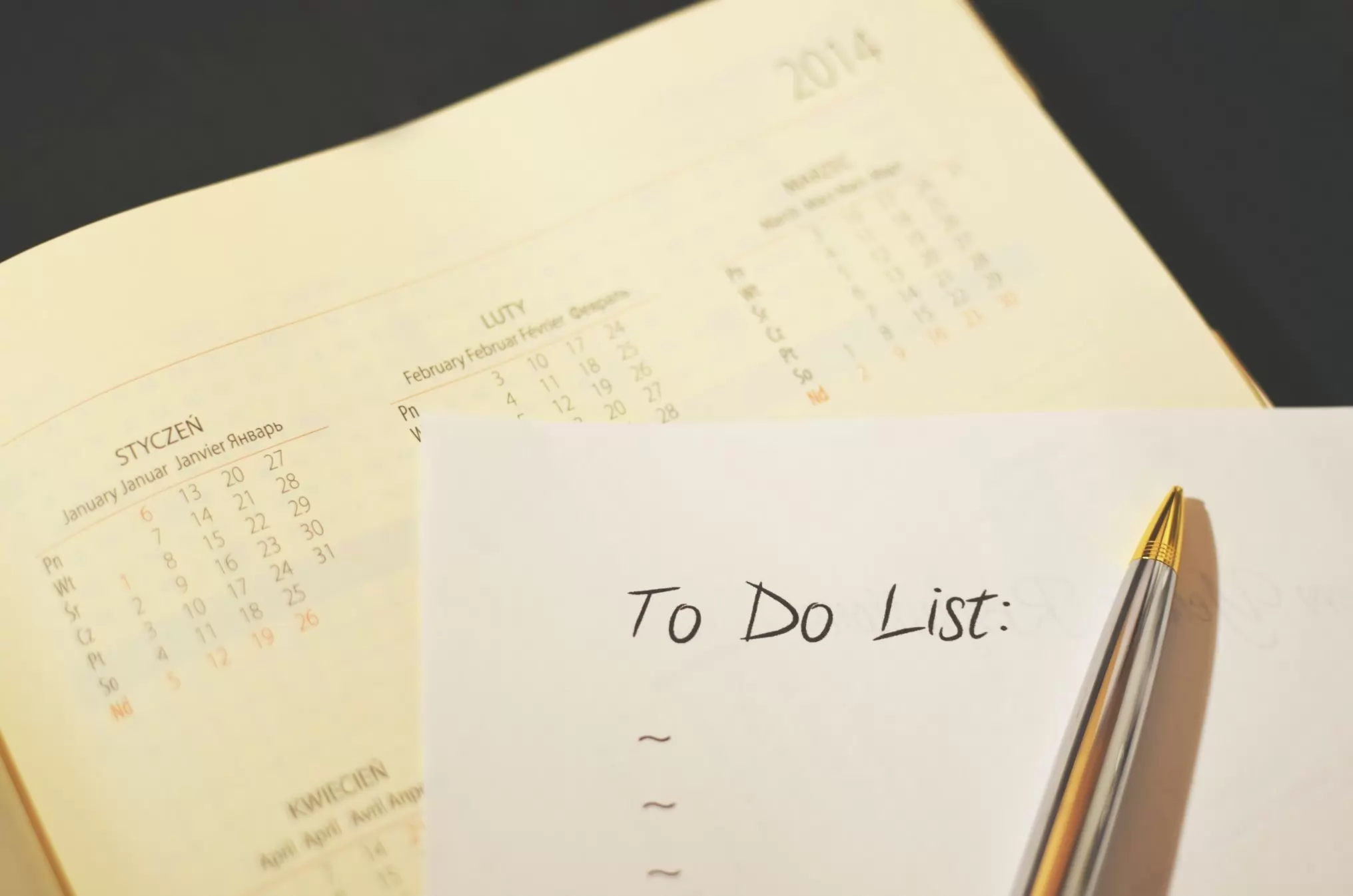 A handwritten to do list in front of a calendar.